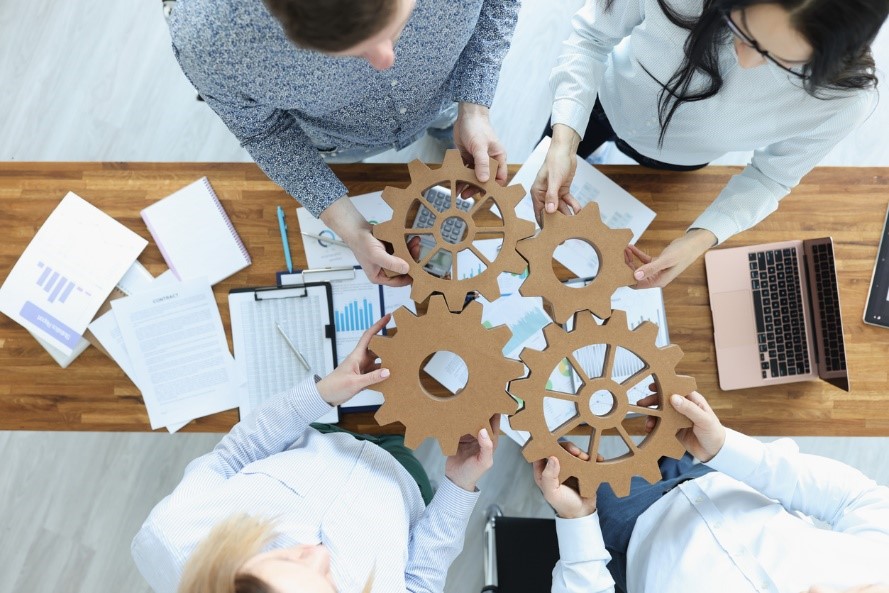 people putting wooden cogs together from above during a meeting